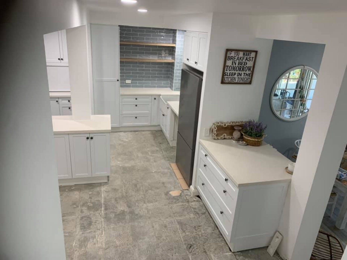 A white shaker kitchen with overhead cabinets and a stone benchtop