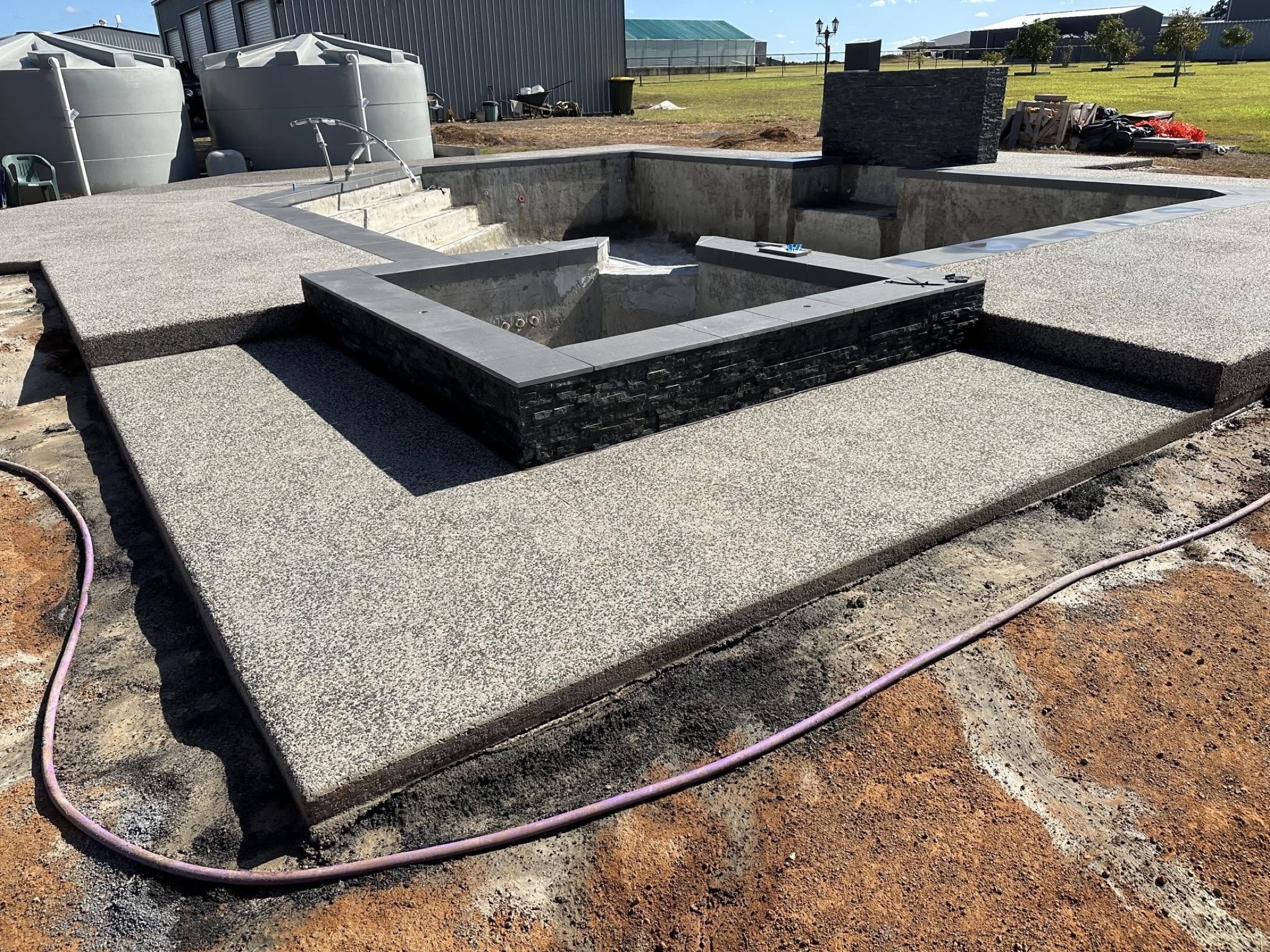 A raised concrete water feature and exposed aggregate surround at a rural property