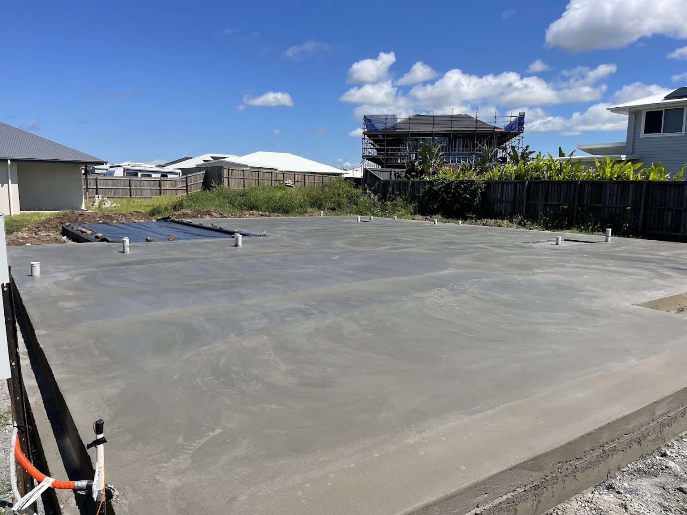 A large freshly poured concrete slab on a block with houses going up behind it