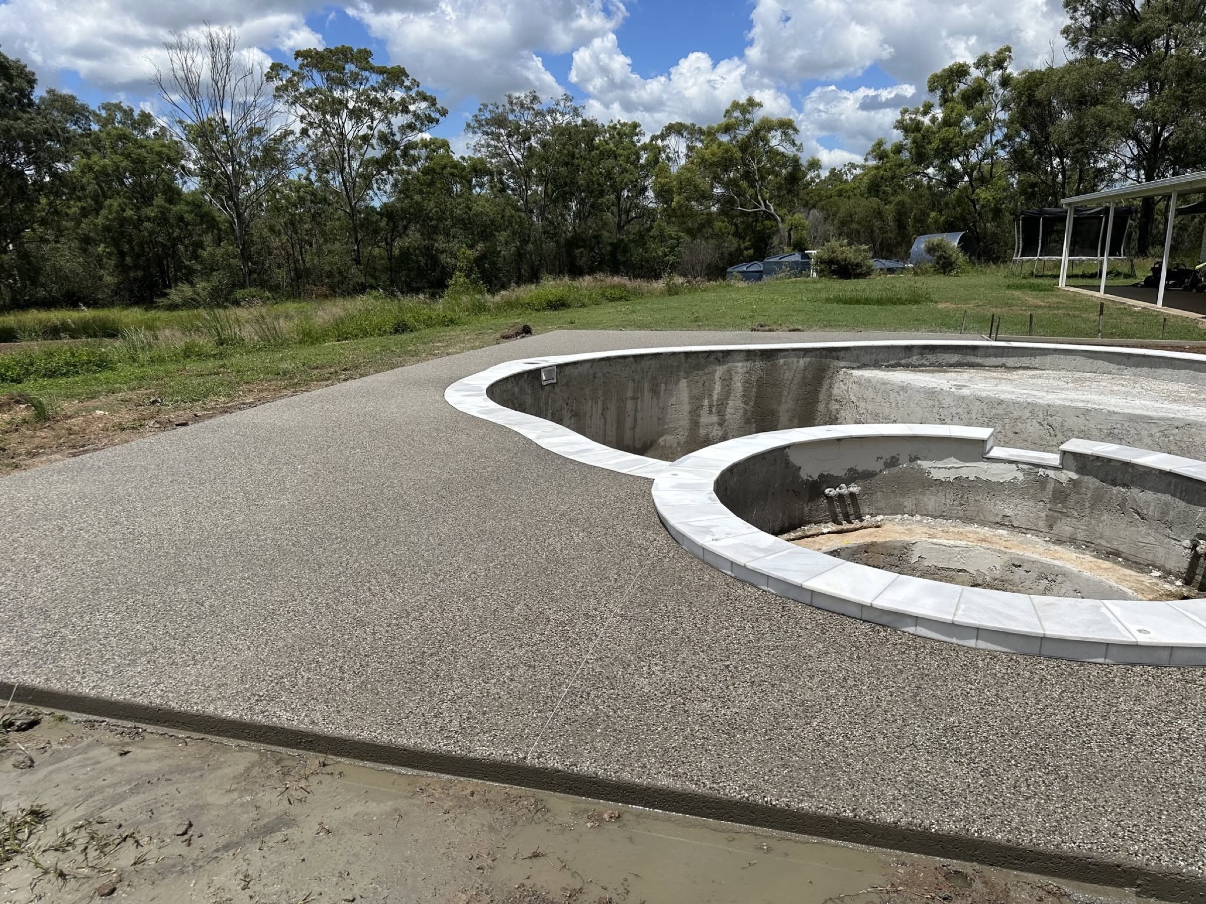 An exposed aggregate apron curving around the edge of a pool shell
