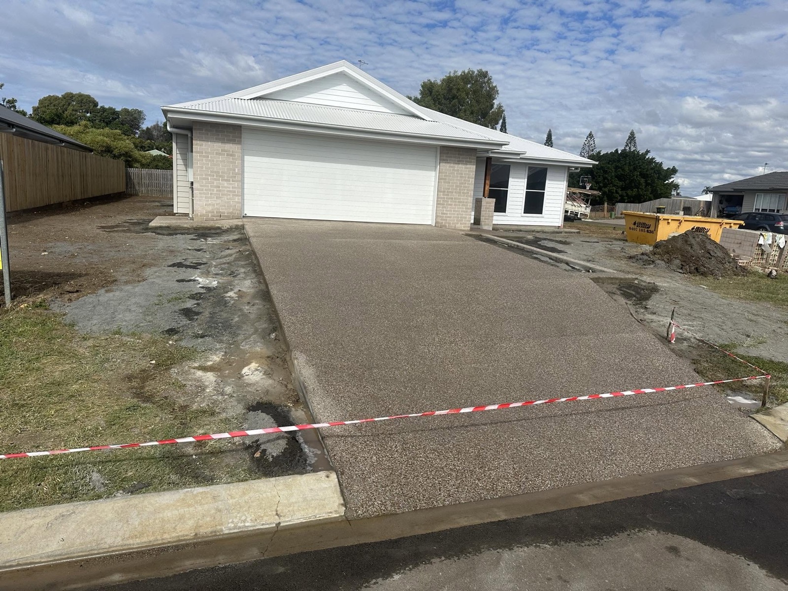 A finished exposed aggregate driveway running to a double garage