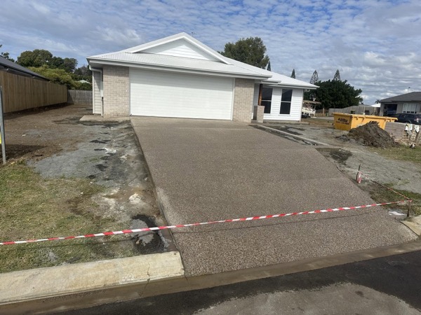 A wide exposed aggregate driveway sloping down to the street