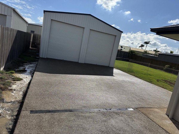 A concrete driveway leading up to a colourbond shed
