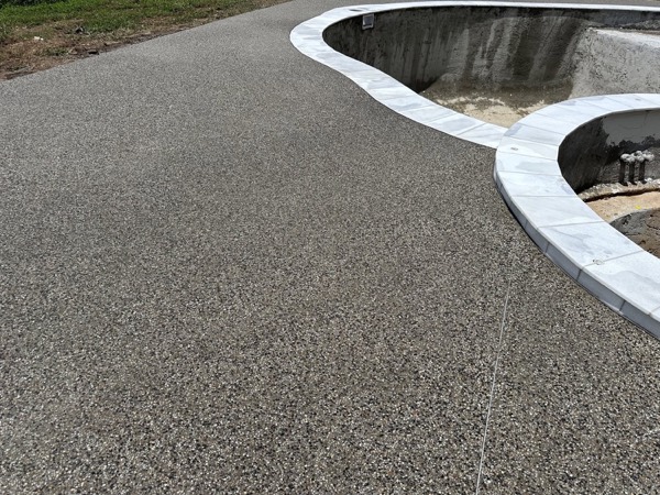 An exposed aggregate pool surround with a white coping edge