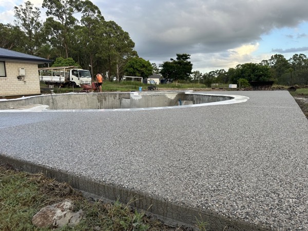 An exposed aggregate pool surround seen across the lawn