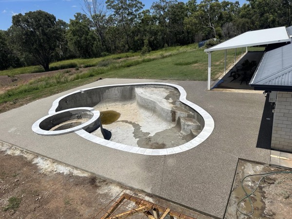 A freeform pool shell with a curved concrete surround