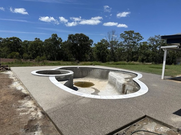 A freeform pool and concrete surround set in an open paddock