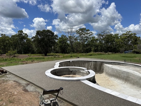 A formed pool shell and round water feature on a cleared site