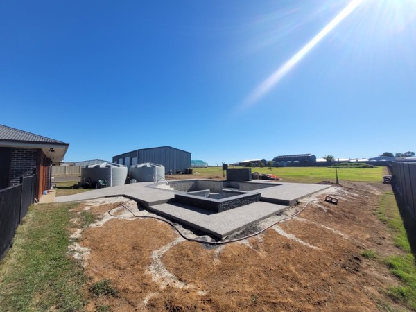 A rural block with a formed concrete pad and water tanks