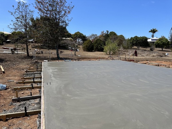 A fresh concrete slab poured on a sloping rural block