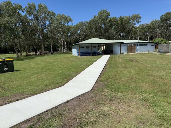 A concrete path crossing lawn to a park building