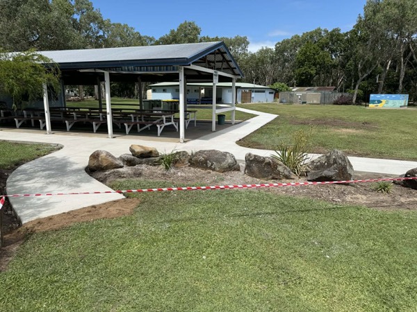 A picnic shelter with new concrete paths through the lawn
