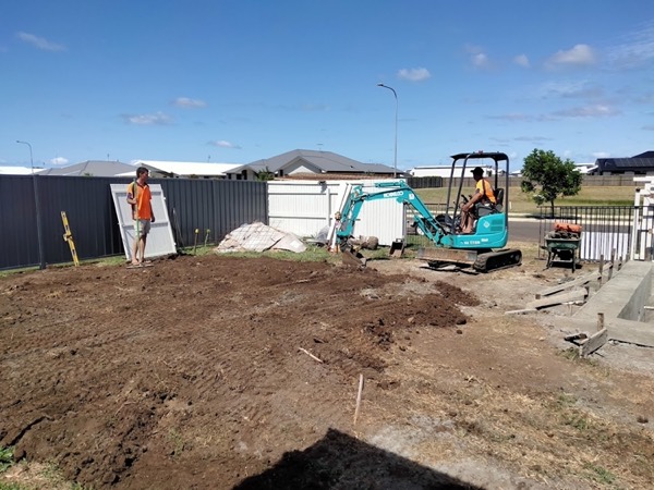 Two workers in high-visibility shirts preparing a site with a mini excavator
