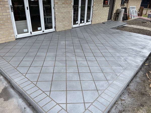 A concrete patio scored in a diamond grid pattern outside bifold doors
