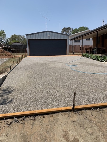 An exposed aggregate driveway leading up to a garage door