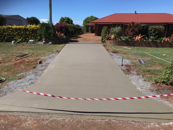 A long concrete path leading to a red-roofed home