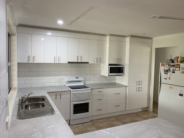 A white kitchen with overhead cabinets, a sink and a freestanding oven