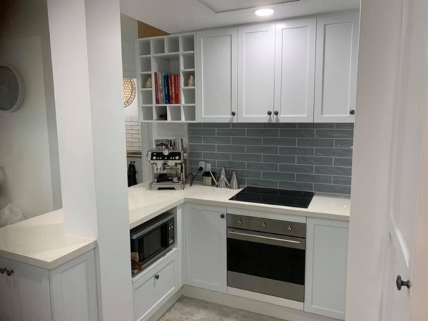 A white kitchen with a grey subway splashback and a wall oven