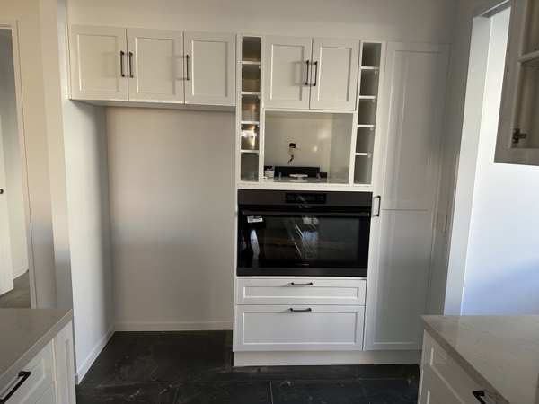 A white kitchen with an appliance tower and built-in wall oven