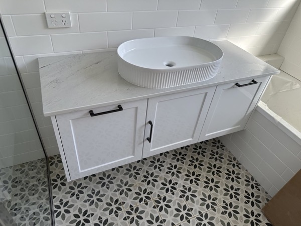 A custom vanity with a stone top and a round above-counter basin