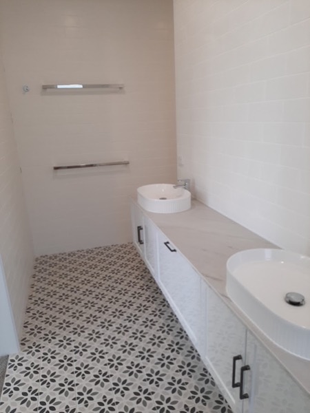 A bathroom vanity with twin basins and patterned floor tiles
