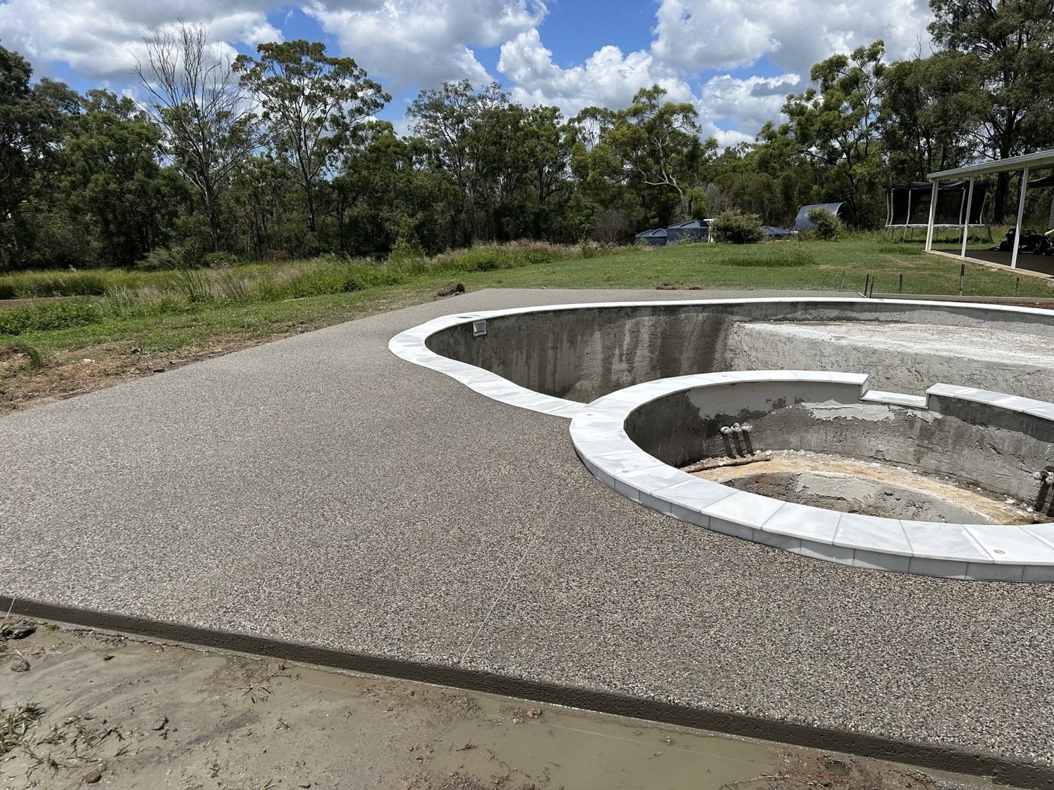 An exposed aggregate apron curving around a pool shell